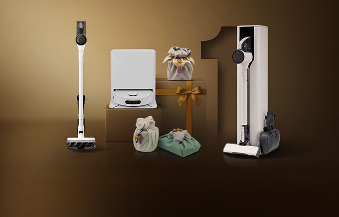 LG 무선 청소기와 로봇 청소기, 전용 거치대가 함께 전시되어 있으며, 다양한 색상의 보자기 포장 선물이 어우러진 고급스러운 브라운 톤 배경 이미지