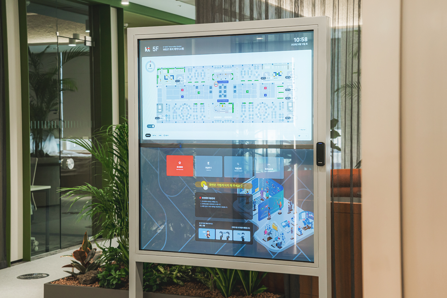 실내 안내용 사이니지 화면 상단 왼쪽에 'KT 5F'가 표시되고 우측 상단에 시간 '10:58'이 보이며, 화면에는 층 평면도와 아이콘들이 배치된 지도 인터페이스가 나타나고 하단 영역에 여러 기능 버튼이 정렬된 모습입니다.