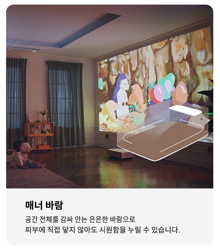 거실에서 가족이 소파에 앉아 벽에 투사된 애니메이션을 보고 있습니다. 애니메이션에는 알록달록한 색상의 캐릭터들이 등장합니다. 오른쪽에는 매너 바람이라는 제목과 함께 공간 전체를 감싸 안는 은은한 바람으로 피부에 직접 닿지 않아도 시원함을 누릴 수 있습니다.라는 설명이 적혀 있습니다.