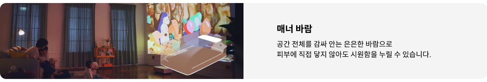 거실에서 가족이 소파에 앉아 벽에 투사된 애니메이션을 보고 있습니다. 애니메이션에는 알록달록한 색상의 캐릭터들이 등장합니다. 오른쪽에는 매너 바람이라는 제목과 함께 공간 전체를 감싸 안는 은은한 바람으로 피부에 직접 닿지 않아도 시원함을 누릴 수 있습니다.라는 설명이 적혀 있습니다.