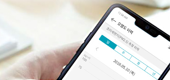 스마트폰 화면에 '모임도 예약'이라는 제목이 보이며, '코엑스몰(WP) 2.5L 성당 예약'이라는 텍스트가 있습니다. 날짜는 '2018.05.10 (목)'로 표시되어 있습니다. 화면 상단에는 시간 '11:25 AM'이 표시되어 있습니다. 배경은 흐릿하게 보이는 손과 테이블이 있습니다.