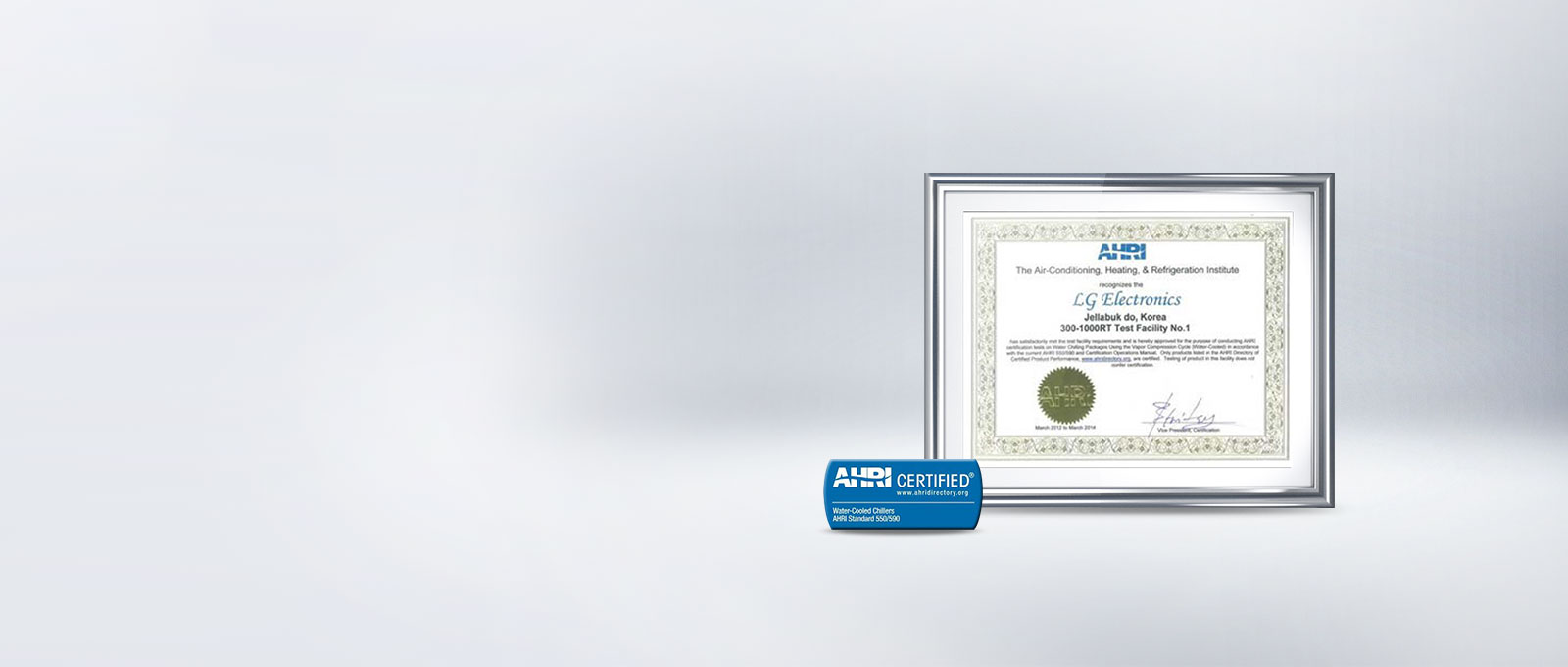 이미지에는 AHRI 인증서가 액자에 담겨 있습니다. 인증서는 The Air-Conditioning, Heating, & Refrigeration Institute recognizes LG Electronics Jeollabuk do, Korea 300-1000RT Test Facility No.1라는 내용을 포함하고 있으며, 인증 날짜는 2014년 3월입니다. 인증서 아래에는 AHRI CERTIFIED® Water-Cooled Chillers AHRI Standard 550/590라는 문구가 적힌 파란색 배지가 있습니다. 배경은 연한 회색입니다.