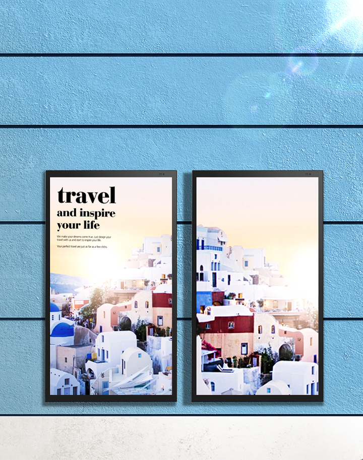파란색 벽에 두 개의 포스터가 걸려 있습니다. 포스터에는 travel and inspire your life라는 문구가 적혀 있으며, 하얀 건물들이 모여 있는 풍경 사진이 있습니다. 벽 아래에는 파란색 자전거가 세워져 있습니다. 벽은 파란색 타일로 구성되어 있고, 바닥은 회색 타일입니다. 빛이 벽에 반사되어 밝은 느낌을 줍니다.