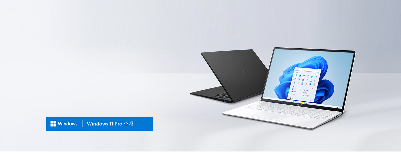 두 대의 노트북이 놓여 있습니다. 앞쪽 노트북은 화면에 Windows 11 운영체제를 실행 중이며, LG 로고가 보입니다. 뒤쪽 노트북은 검은색입니다. 이미지 하단에는 파란색 배너에 Windows | Windows 11 Pro 소개라는 텍스트가 포함되어 있습니다.