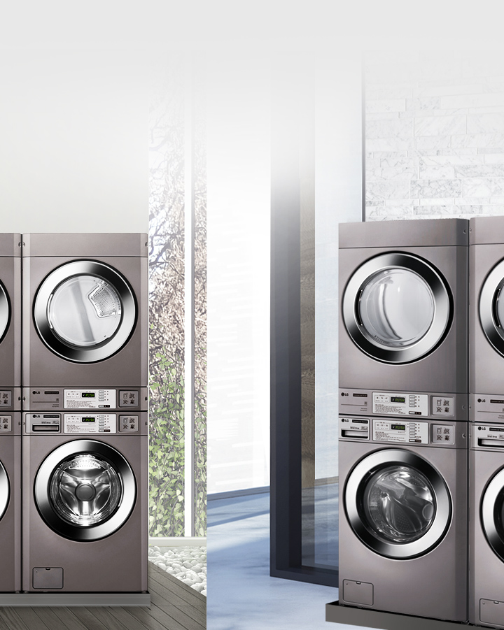 세탁기와 건조기가 쌓여 있는 모습입니다. 각 기기는 금속성 외관을 가지고 있으며, 투명한 문을 통해 내부가 보입니다. 기기 앞면에는 조작 버튼과 디지털 디스플레이가 있습니다. 배경에는 큰 유리창과 벽돌 무늬의 벽이 보입니다.