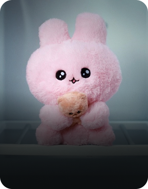 웃는 모습의 분홍색 토끼 인형인 최고심이 정면을 응시하며 앉아있습니다.