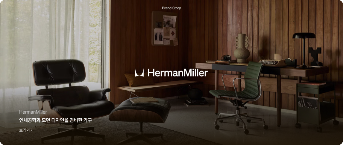 어두운 톤의 우드 패널 벽면으로 마감된 중후하고 고급스러운 서재 인테리어 이미지입니다.
이미지 상단 중앙에는 'Brand Story' 문구가 있고, 중앙에는 흰색 'HermanMiller' 로고가 배치되어 있습니다.
좌측에는 검은색 가죽 라운지 체어와 오토만이 놓여 있고 큰 창을 통해 은은한 자연광이 들어오며, 우측에는 데스크와 녹색 사무용 의자, 타자기, 스탠드 조명 등 다양한 소품이 감각적으로 배치되어 있습니다.
좌측 하단에는 'HermanMiller', '인체공학과 모던 디자인을 겸비한 가구'라는 문구와 밑줄이 그어진 '보러가기' 링크가 있습니다.
