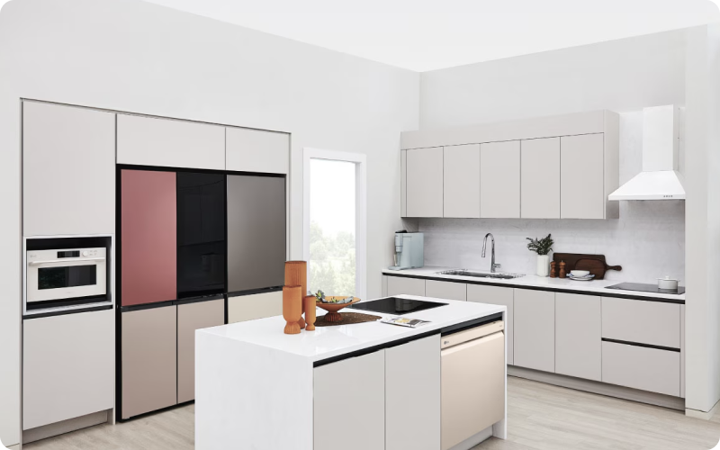 화이트와 베이지 톤으로 꾸며진 넓고 깨끗한 주방 전경 사진. 좌측 빌트인 수납장에는 화이트 색상의 광파오븐과 핑크, 블랙, 그레이 등 다양한 컬러 패널이 조합된 4도어 LG 오브제컬렉션 냉장고가 설치되어 있음. 중앙의 화이트 아일랜드 식탁에는 인덕션과 베이지색 LG 식기세척기가 빌트인 되어 있으며, 우측 메인 주방 조리대에는 싱크대 수전, 민트색 정수기, 인덕션, 그리고 상단의 화이트 주방 후드가 조화롭게 배치되어 있음.