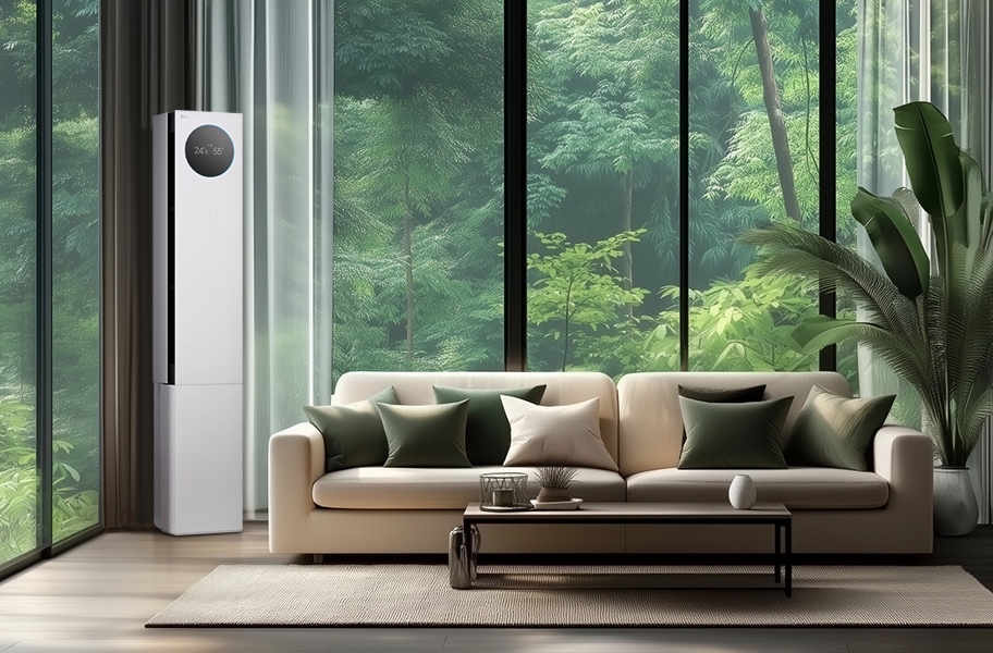 LG 휘센 AI 오브제컬렉션 뷰I 프로 에어컨이 거실의 왼쪽 구석에 세워져 있으며, 에어컨의 원형 디스플레이에는 24.5°C와 55%라는 숫자가 표시되어 있습니다. 에어컨 옆으로는 큰 창문이 있어 푸른 숲의 풍경이 보이며, 창문 앞에는 베이지색 소파가 놓여 있습니다. 소파 위에는 여러 개의 녹색과 흰색 쿠션이 배열되어 있고, 소파 앞에는 낮은 테이블이 놓여 있습니다. 테이블 위에는 장식품과 책이 놓여 있으며, 오른쪽에는 큰 화분에 심어진 녹색 식물이 배치되어 있습니다.