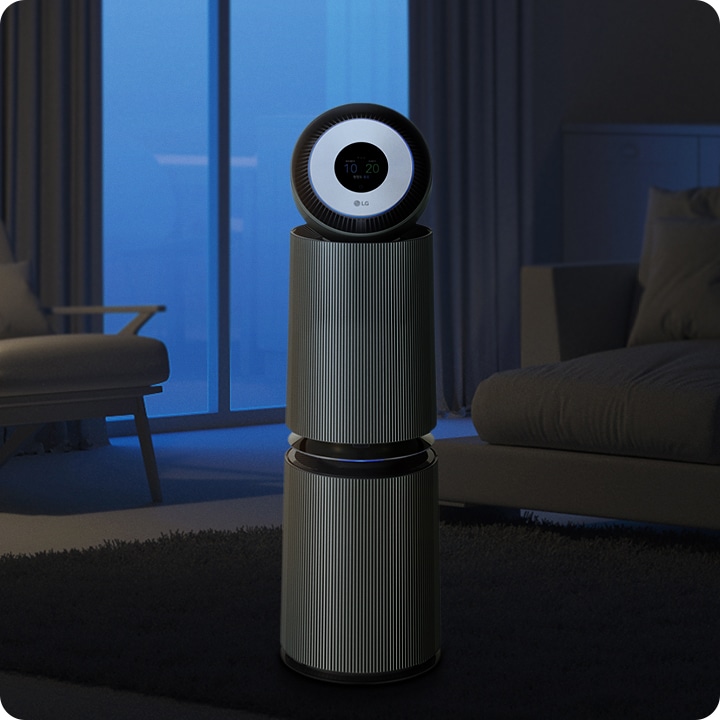 세련된_디자인의_공기청정기가_어두운_실내에_놓여_있습니다._공기청정기의_상단에는_원형_디스플레이가_있으며,_10과_20이라는_숫자가_표시되어_있습니다._주변에는_커튼이_드리워진_창문과_소파가_보입니다.