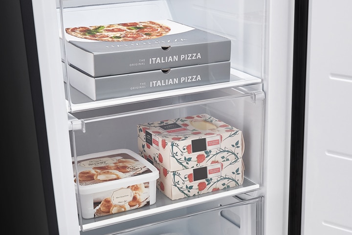 냉장고 안에 피자 상자 두 개가 쌓여 있으며, "ITALIAN PIZZA"라는 글자가 적혀 있습니다. 그 아래에는 꽃무늬가 있는 상자 두 개와 아이스크림 용기가 놓여 있습니다.