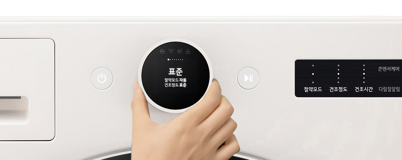 손이 조작하는 세탁기 조작부가 보입니다. Objet라는 로고가 있으며, 전원 버튼과 재생 버튼이 있습니다. 원형 디스플레이에는 표준, 절약모드 자동, 건조정도 표준이라는 텍스트가 표시되어 있습니다. 콘덴서케어, 절약모드, 건조정도, 건조시간, 다림질알림이라는 텍스트가 보입니다.