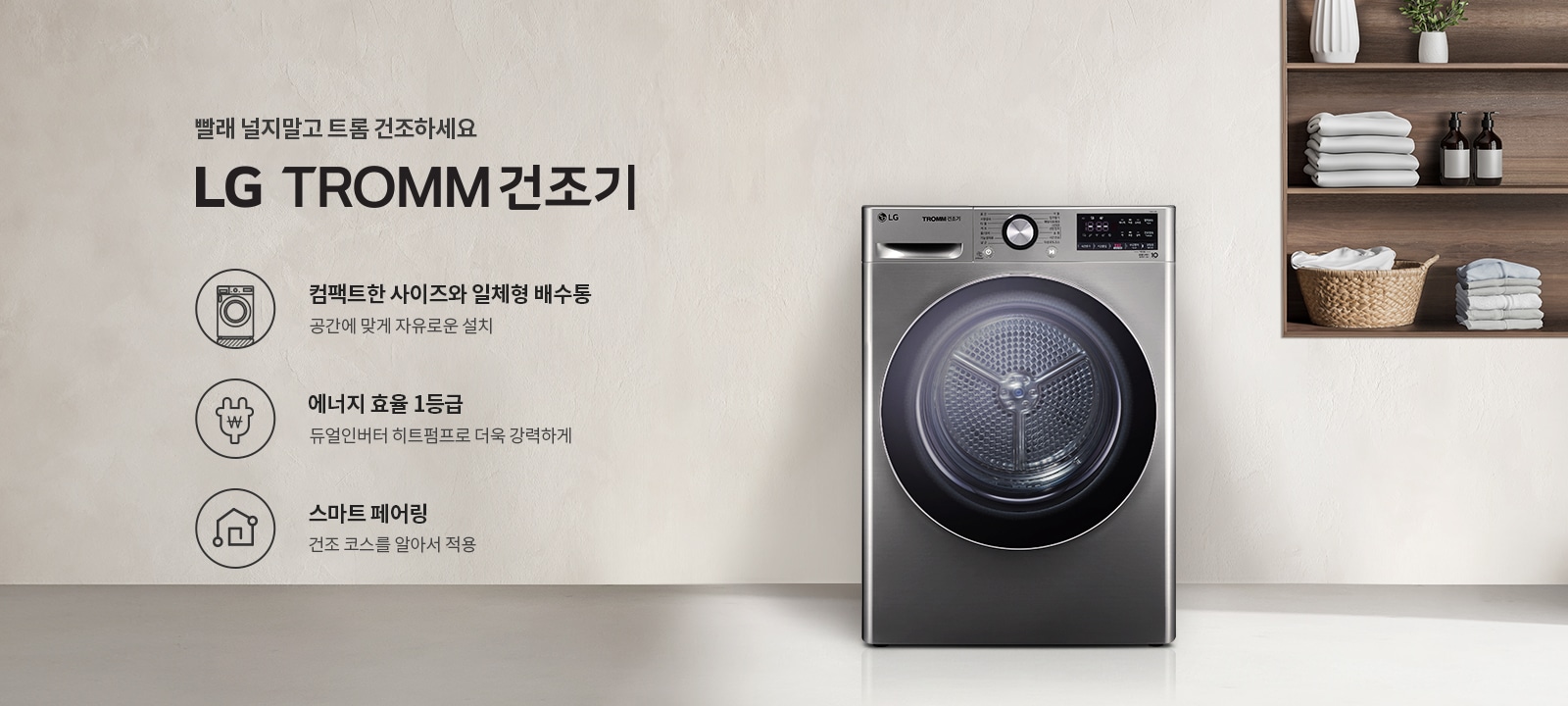 빨래 널지말고 트롬 건조하세요. LG TROMM 건조기. 컴팩트한 사이즈와 일체형 배수통, 공간에 맞게 자유로운 설치. 에너지 효율 1등급, 듀얼인버터 히트펌프로 더욱 강력하게. 스마트 페어링, 건조 코스를 알아서 적용. 배경에는 금속성의 LG 건조기와 선반에 접힌 수건과 장식품들이 놓여 있습니다.