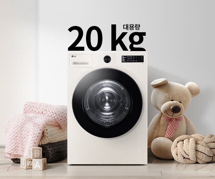세탁기가 놓여 있으며, 20kg 대용량이라는 텍스트가 있습니다. 세탁기 주변에는 분홍색 담요와 곰 인형이 있고, 바닥에는 알파벳 블록이 놓여 있습니다. 배경은 밝은 색상의 벽과 그림이 걸려 있습니다.