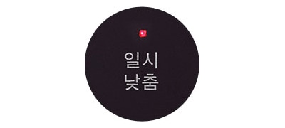 검은색 원 안에 일시 낮춤이라는 흰색 글자가 적혀 있습니다. 원의 상단에는 작은 빨간색 불빛이 보입니다.