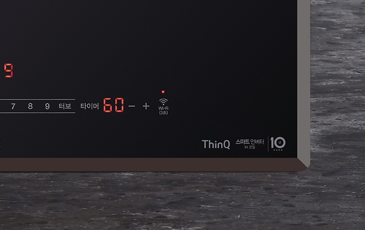 검은색 패널에 빨간색 숫자와 아이콘이 표시되어 있습니다. 숫자 60과 Wi-Fi 아이콘이 보이며, ThinQ 스마트 인버터 버블힐링이라는 문구와 10년 무상보증이라는 텍스트가 있습니다. 바닥은 회색의 질감 있는 표면입니다.