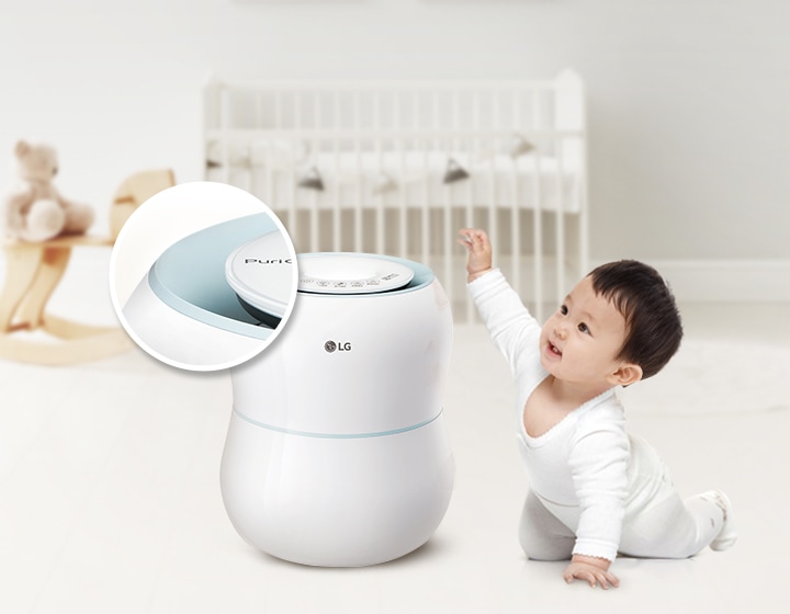 아기가 바닥에 앉아 가습기를 바라보며 손을 뻗고 있습니다. 가습기에는 'LG' 로고가 있으며, 확대된 이미지에는 'PuriCare'라는 텍스트가 보입니다. 배경에는 아기 침대와 목마가 놓여 있습니다.
