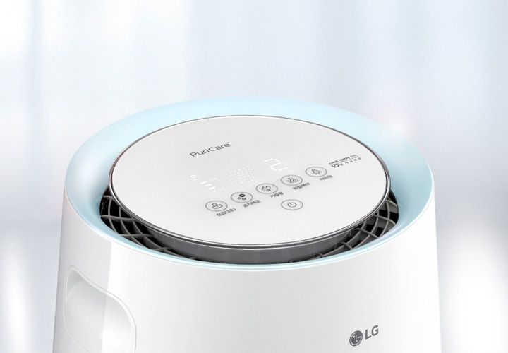 LG 로고가 있는 가습기의 상단부가 보입니다. 상단에는 PuriCare라는 텍스트와 함께 여러 개의 버튼이 있으며, 버튼에는 잠금, 공기제균, 가습량, 취침예약, 라이팅 기능이 표시되어 있습니다. 배경은 부드러운 흰색과 파란색 톤으로 구성되어 있습니다.