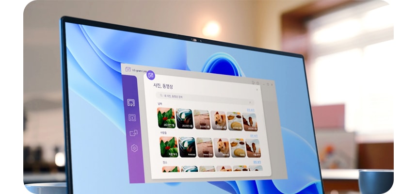 컴퓨터 모니터 화면에 사진, 동영상이라는 제목의 프로그램 창이 열려 있으며, 여러 개의 사진 미리보기가 보입니다. LG gram Link라는 텍스트가 있고, 아이콘들이 나열되어 있습니다. 배경은 실내 공간으로, 흐릿하게 보이는 창문과 조명이 있습니다.