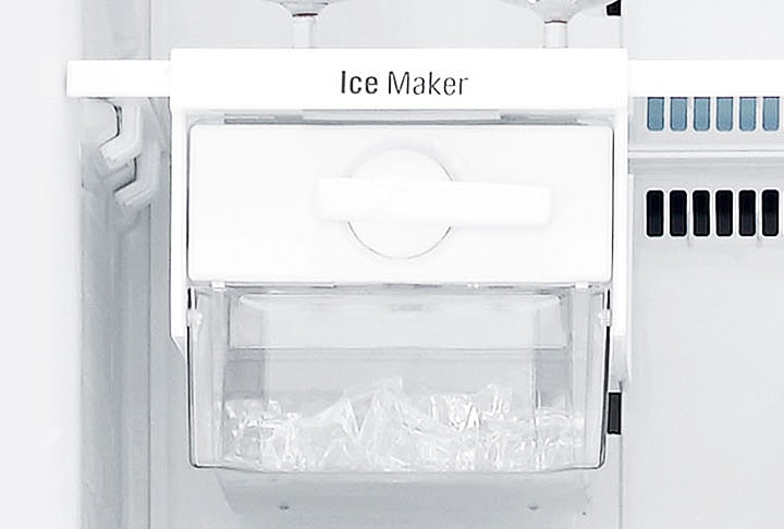 냉장고 내부에 설치된 얼음 제조기가 보입니다. Ice Maker라는 텍스트가 상단에 적혀 있으며, 투명한 용기 안에는 얼음이 담겨 있습니다. 주변은 흰색으로 깔끔하게 마감되어 있습니다.