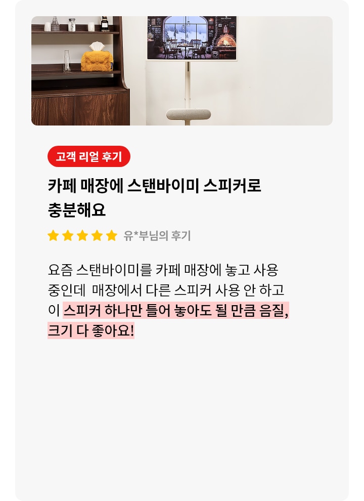 스탠바이미 스피커 제품에 대한 리뷰 컨텐츠입니다. 리뷰 사진에는 스탠바이미 제품과 스피커가 보입니다. 화면에는 창문 밖으로 눈 내리는 풍경이 보이는 아늑한 카페 내부가 그려져 있습니다. 벽난로에는 불이 지펴져 있고, 따뜻한 조명들이 보입니다. TV 아래에는 길고 둥근 베이지색 스피커가 놓여 있습니다. 왼쪽에는 나무색 책장이 있으며, 그 위에 책과 장식품들이 진열되어 있습니다. 상세내용은 하단 참고.
