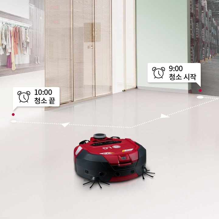빨간색_로봇_청소기가_바닥을_청소하고_있으며,_바닥에는_청소_시작_위치라는_텍스트가_있는_위치_표시_아이콘이_보입니다._주변에는_신발과_가방이_놓인_흰색_가구가_있고,_검은색_부츠가_진열된_선반이_있습니다._바닥은_나무_재질로_보입니다.