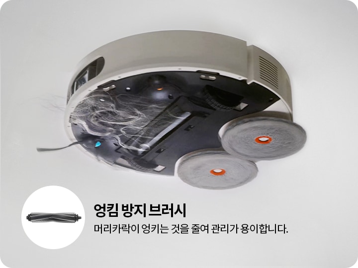 로봇 청소기의 하단 모습이 보이며, 두 개의 회전 브러시와 머리카락이 엉킨 부분이 있습니다. 왼쪽에는 엉킴 방지 브러시라는 텍스트와 함께 브러시 이미지가 있고, 머리카락이 엉키는 것을 줄여 관리가 용이합니다.라는 설명이 포함되어 있습니다.