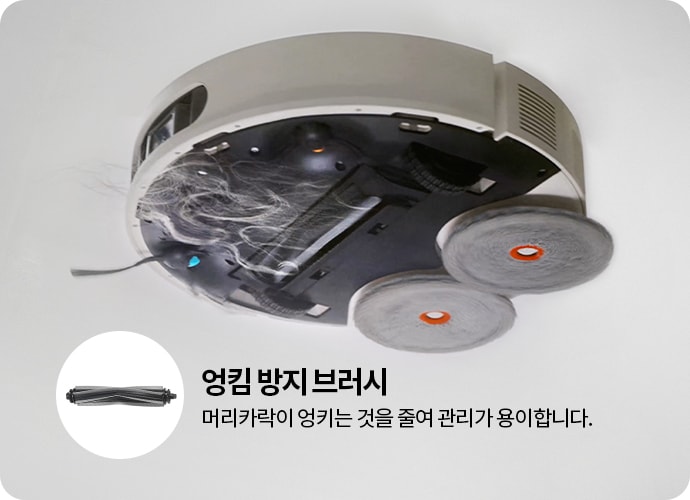 로봇 청소기의 하단 모습이 보이며, 두 개의 회전 브러시와 머리카락이 엉킨 부분이 있습니다. 왼쪽에는 엉킴 방지 브러시라는 텍스트와 함께 브러시 이미지가 있고, 머리카락이 엉키는 것을 줄여 관리가 용이합니다.라는 설명이 포함되어 있습니다.