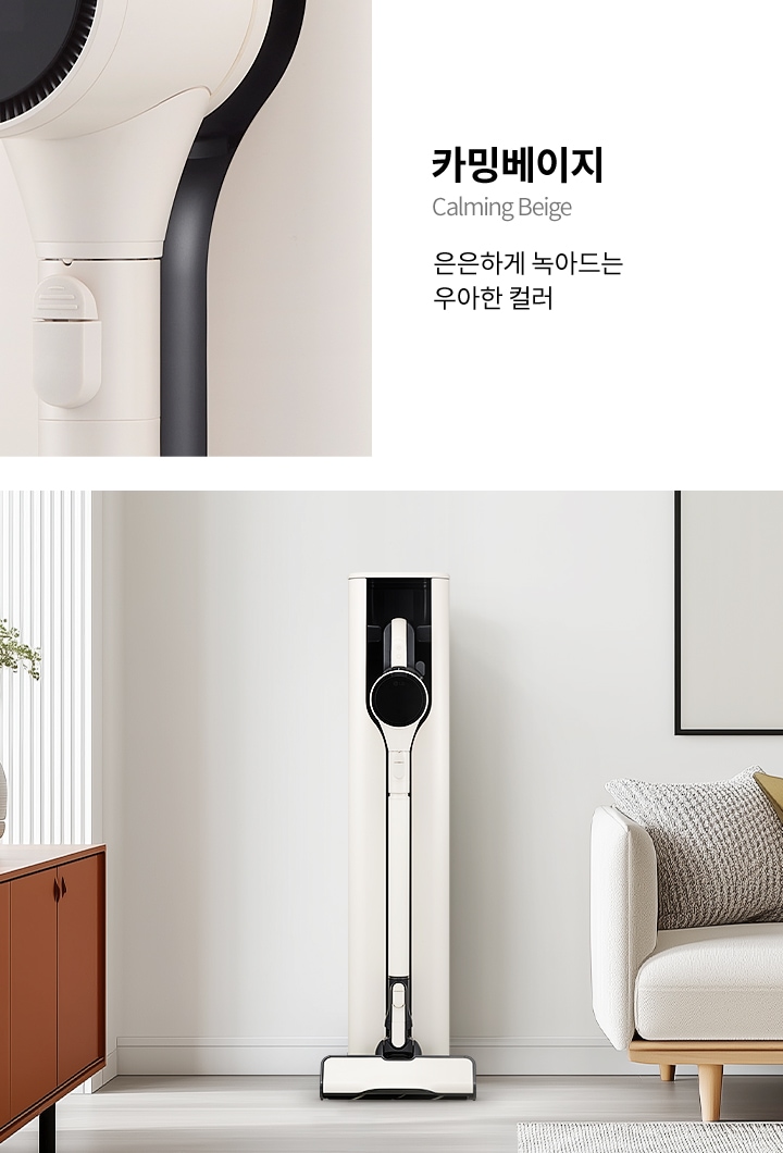 세련된 실내 공간에 스탠드형 청소기가 놓여 있으며, 옆에는 베이지색의 소파와 서랍장이 있습니다. 서랍장 위에는 장식품이 있고 소파 위 벽에는 액자가 걸려있습니다. 