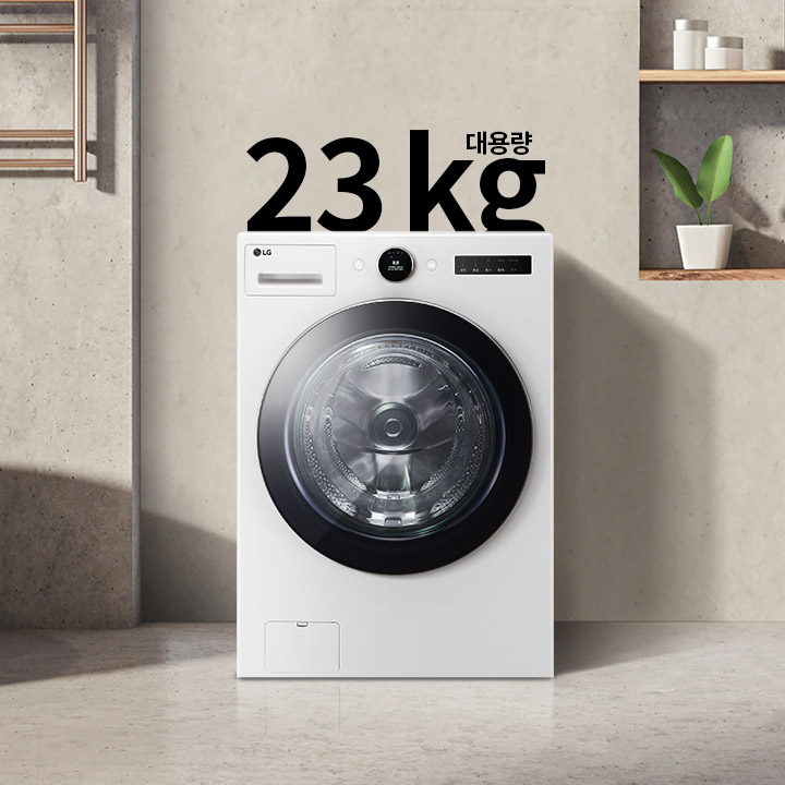 세탁기가 욕실에 놓여 있으며, 세탁기 위에는 대용량 23kg라는 글자가 있습니다. 세탁기 옆에는 욕조가 있고, 벽 선반에는 화분과 용기가 놓여 있습니다. 수건이 걸려 있는 모습도 보입니다.