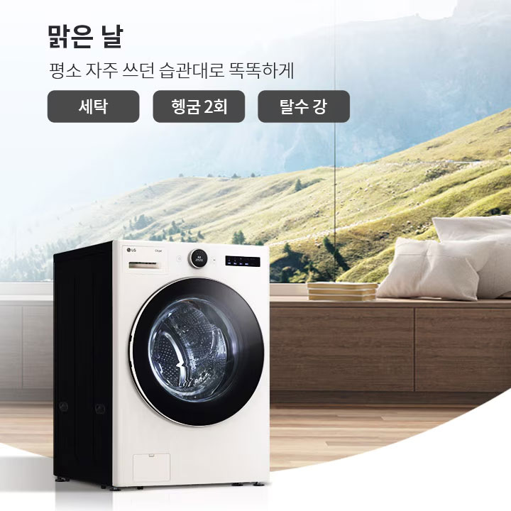 세탁기가 나무 바닥 위에 놓여 있으며, 뒤로는 큰 창문을 통해 산과 푸른 초원이 보입니다. 창문 옆에는 쿠션이 놓인 벤치가 있습니다. 