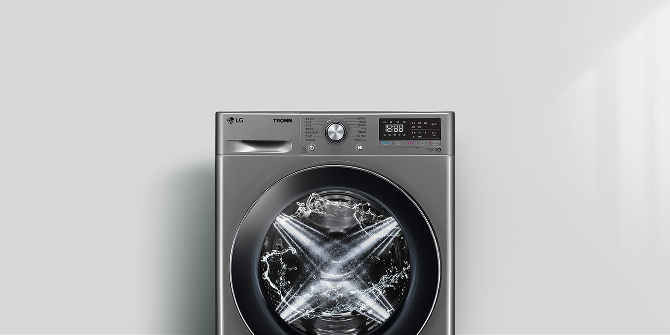 LG 트롬 세탁기가 보입니다. 세탁기 문 안쪽에는 물이 회전하며 세탁이 진행 중인 모습이 보입니다. 세탁기 상단에는 다양한 세탁 모드와 설정을 위한 다이얼과 디지털 디스플레이가 있습니다. 디스플레이에는 시간과 여러 설정 옵션이 표시되어 있습니다. 