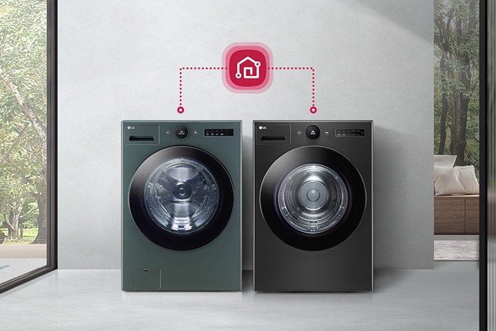 흰색과 검은색 세탁기가 나란히 놓여 있으며, 위쪽에 스마트홈 아이콘이 연결된 모습입니다. 배경으로는 큰 창문을 통해 나무가 보이고, 실내에는 소파와 쿠션이 있습니다. 세탁기에는 LG와 AI DD라는 텍스트가 표시되어 있습니다.
