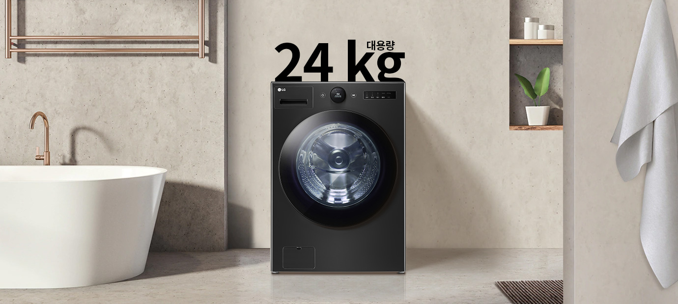 세탁기가 욕실에 놓여 있으며, 세탁기 위에 24 kg 대용량이라는 글자가 있습니다. 욕실에는 욕조와 수건이 걸려 있고, 벽 선반에는 화분과 용기가 놓여 있습니다.