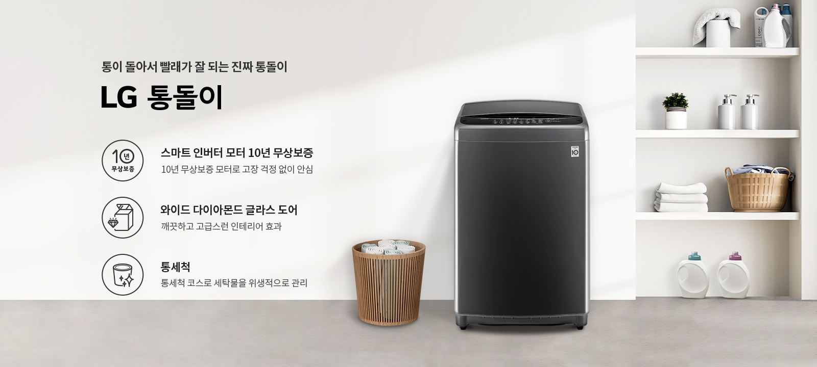 통이 돌아서 빨래가 잘 되는 진짜 통돌이 LG 통돌이. 스마트 인버터 모터 10년 무상보증, 10년 무상보증 모터로 고장 걱정 없이 안심. 와이드 다이아몬드 글라스 도어, 깨끗하고 고급스러운 인테리어 효과. 통세척, 통세척 코스로 세탁물을 위생적으로 관리. 검정색 세탁기가 있으며, 세탁기 옆에는 수건이 담긴 바구니가 놓여 있습니다. 배경에는 여러 가지 세제와 수건이 정리된 선반이 보입니다.