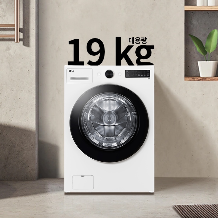 세탁기가 욕실에 놓여 있으며, 세탁기 위에는 19 kg 대용량이라는 텍스트가 있습니다. 세탁기 옆에는 욕조와 수건이 걸려 있고, 벽 선반에는 화분과 용기가 놓여 있습니다.