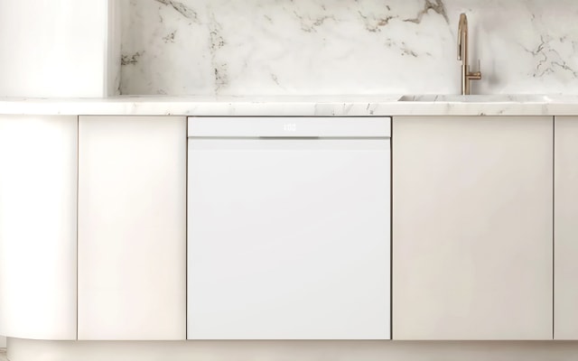 아이보리색 주방 가구의 정면 모습으로, 식기세척기가 빌트인되어 있고 위에는 대리석 조리대가 보입니다.