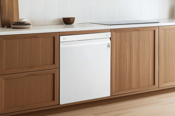 밝은 나무 프레임과 하얀 상판을 가진 현대적인 주방 배경으로, 화이트 색상 식기세척기가 나무 패널 캐비닛 사이에 설치되어 있습니다.