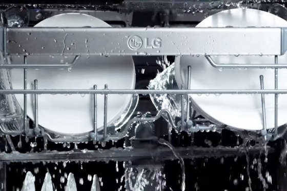 식기세척기 내부에서 물이 뿌려지고, 상단 선반에 놓여 있는 접시와 유리잔에 물방울이 맺혀 있는 모습.