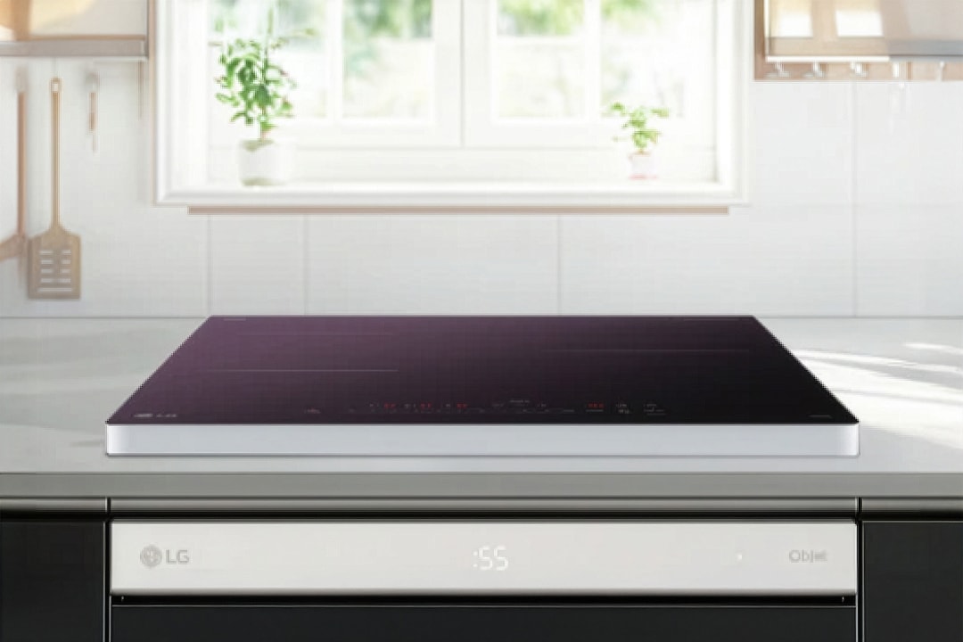 검은색 상판의 인덕션이 밝은 주방 조리대 위에 깔끔하게 설치되어 있습니다. 상판에는 원형·십자 형태의 조리 구역 표시와 함께 전원, 화력 조절, 타이머 등의 터치 아이콘이 얇고 정교하게 배치되어 있습니다.