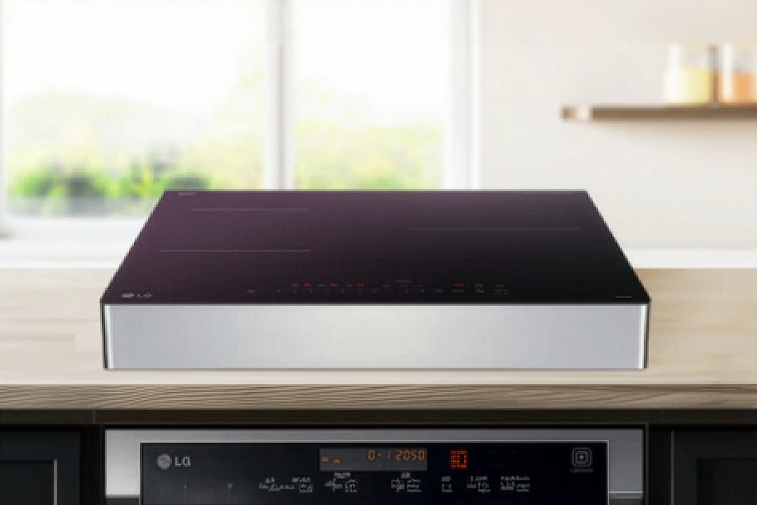 검은색 상판의 인덕션이 밝은 주방 조리대 위에 깔끔하게 설치되어 있습니다. 상판에는 원형·십자 형태의 조리 구역 표시와 함께 전원, 화력 조절, 타이머 등의 터치 아이콘이 얇고 정교하게 배치되어 있습니다.