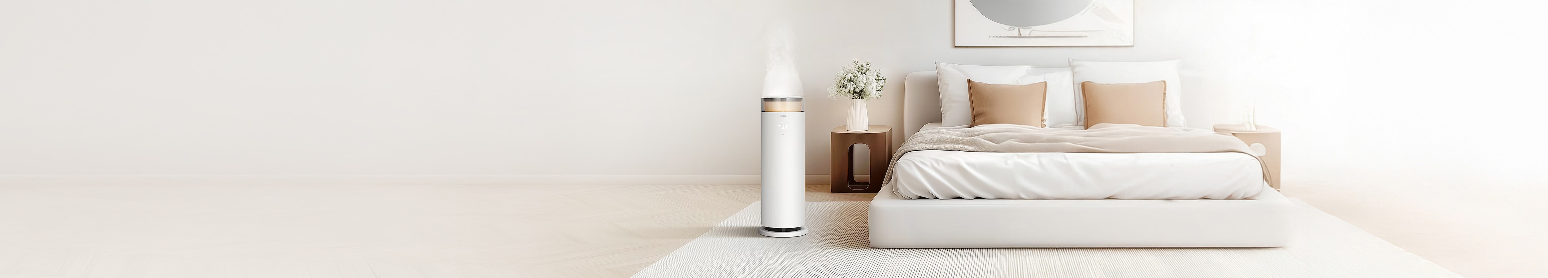 침실에 위치한 LG 퓨리케어 하이드로에센셜 가습기로, 상단에서 미세한 수증기가 분사되고 있습니다. 침대 옆 협탁에는 흰색 꽃병에 담긴 꽃이 장식되어 있으며, 침대는 흰색 침구로 깔끔하게 정리되어 있습니다. 바닥에는 흰색과 회색 줄무늬가 있는 러그가 깔려 있어 전체적으로 차분하고 깨끗한 분위기를 연출하고 있습니다.