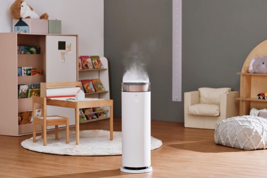 어린이 가구를 배경으로 LG 퓨리케어 하이드로에센셜 가습기가 작동 중인 모습입니다. 가습기 상단에서 수증기가 부드럽게 뿜어져 나오고 있으며, 주변에는 어린이용 책상, 의자, 책장, 인형 등이 배치되어 있습니다.
