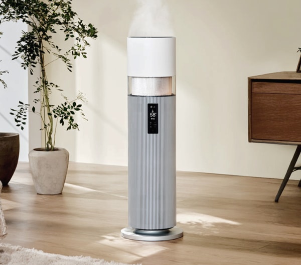 밝은색 실내에 위치한 LG 퓨리케어 하이드로타워 가습기로, 상단에서 수증기가 분사되고 있으며, 전면에 디지털 디스플레이가 보입니다.