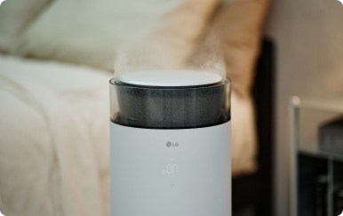 LG 퓨리케어 하이드로에센셜 가습기의 전경으로, 흰색 원통형 본체 상단에서 미세한 수증기가 분출되고 있는 이미지