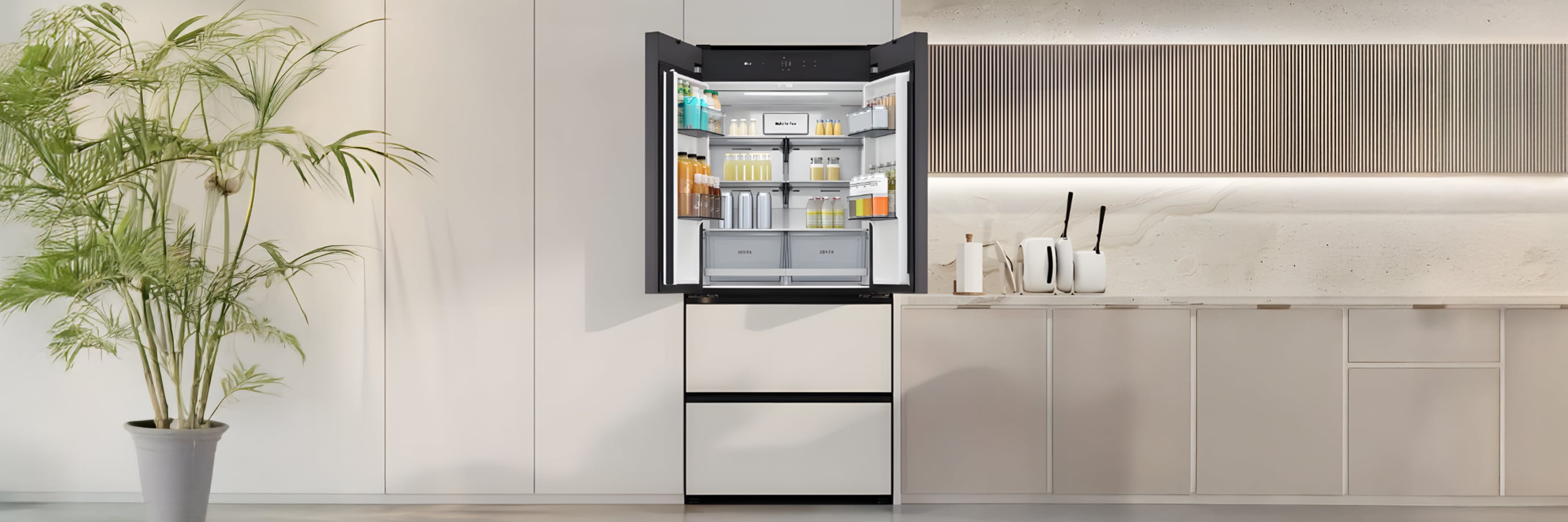 베이지 톤의 주방 공간으로, 중앙에는 도어가 열린 매트 화이트 프렌치도어 김치냉장고가 설치되어 있습니다. 냉장고 내부에는 음료와 유제품이 카테고리별로 정돈되어 있으며, 투명한 선반과 서랍 구조로 내용물이 깔끔하게 진열되어 있습니다. 왼쪽에는 대형 화분이 놓여 자연의 요소를 더하고, 오른쪽에는 간결한 조리대와 수납장이 일체감 있게 구성되어 모던하고 미니멀한 분위기를 연출합니다.