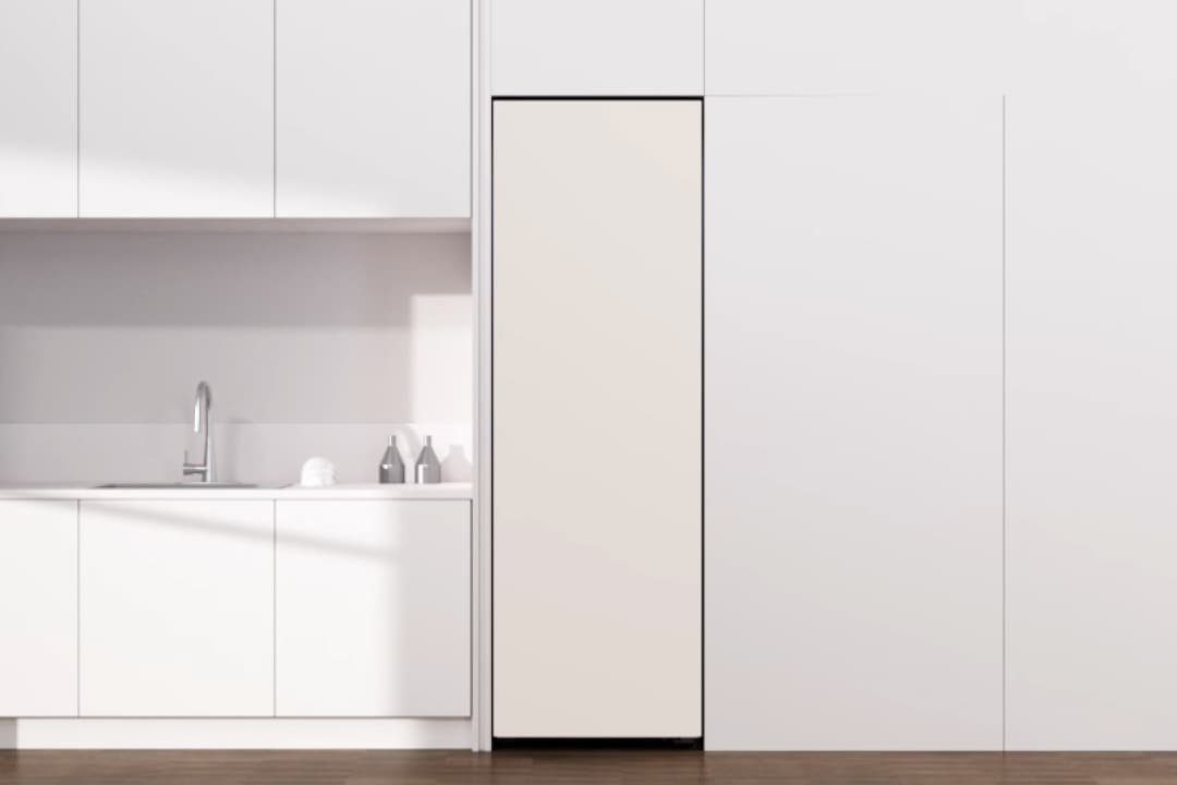 올화이트 컬러로 구성된 미니멀한 주방 공간으로, 오른쪽에는 벽과 일체화된 슬림한 빌트인 김치냉장고가 설치되어 있습니다. 왼쪽에는 상·하부장과 싱크대가 깔끔하게 구성되어 있으며, 스테인리스 수전이 심플한 디자인을 강조합니다. 바닥은 짙은 우드 톤으로 마감되어 전체 공간에 따뜻한 대비감을 더합니다.