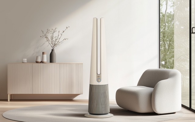 실내 거실 공간에 원형 러그 위에 LG 퓨리케어 오브제컬렉션 에어로타워 Hit 제품이 배치되어 있습니다.공기청정기는 하단은 회색 세로 줄무늬, 상단은 아이보리색의 긴 타워형이며, 옆에 놓인 1인용 소파는 아이보리색의 둥근 형태입니다. 배경에는 나무 캐비닛과 화병이 있고, 창문을 통해 녹색 외부 풍경이 보입니다.