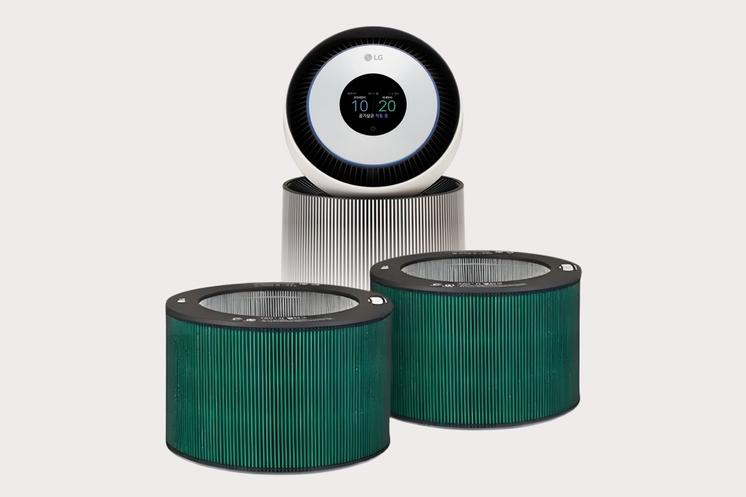 LG 공기청정기와 함께 그에 사용되는 원형 필터 두 개가 전면에 배치된 모습입니다. 공기청정기 상단에는 원형 디스플레이가 있으며, 작동 상태를 직관적으로 보여주는 아이콘과 수치가 표시되어 있습니다. 앞쪽에 놓인 두 개의 필터는 정화 기능을 담당하는 핵심 부품으로, 다층 구조의 그린 컬러 필터가 미세먼지와 유해물질을 효과적으로 걸러내는 기능을 시각적으로 강조합니다.