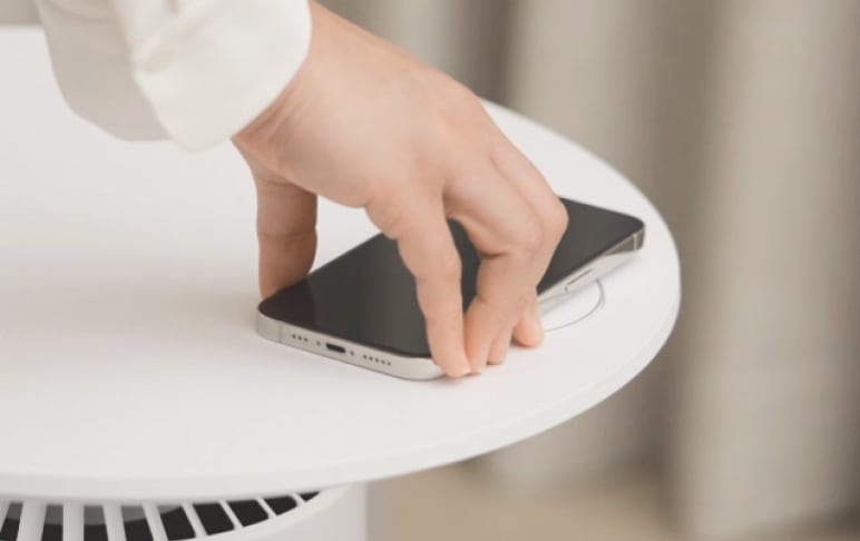 공기청정기 위 테이블에서 스마트폰을 충전하는 장면